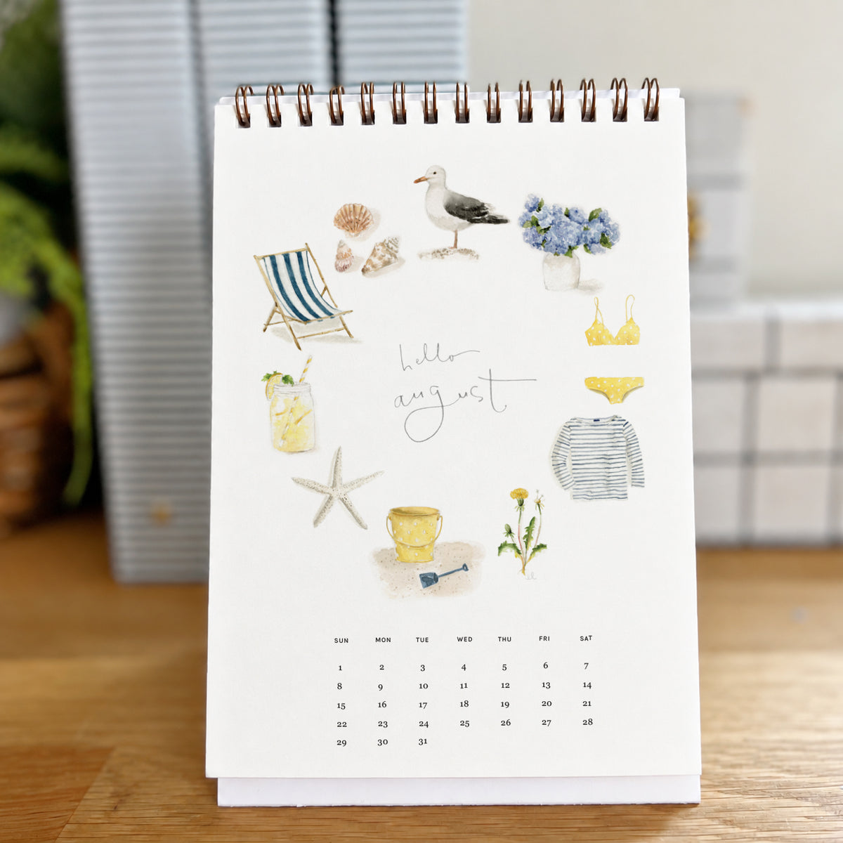 2027 hello month desk calendar August page with watercolor beach icons like a seagull, shells, and a beach chair