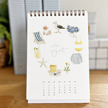 2027 hello month desk calendar August page with watercolor beach icons like a seagull, shells, and a beach chair