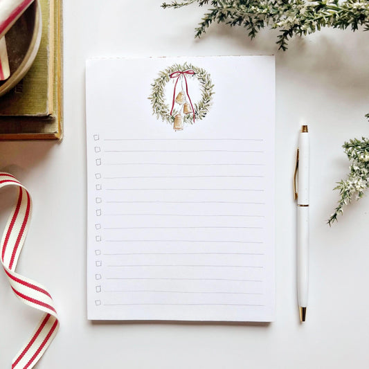 Christmas checklist notepad in the bell wreath design with a watercolor wreath, red bow, and bells above checkbox lines