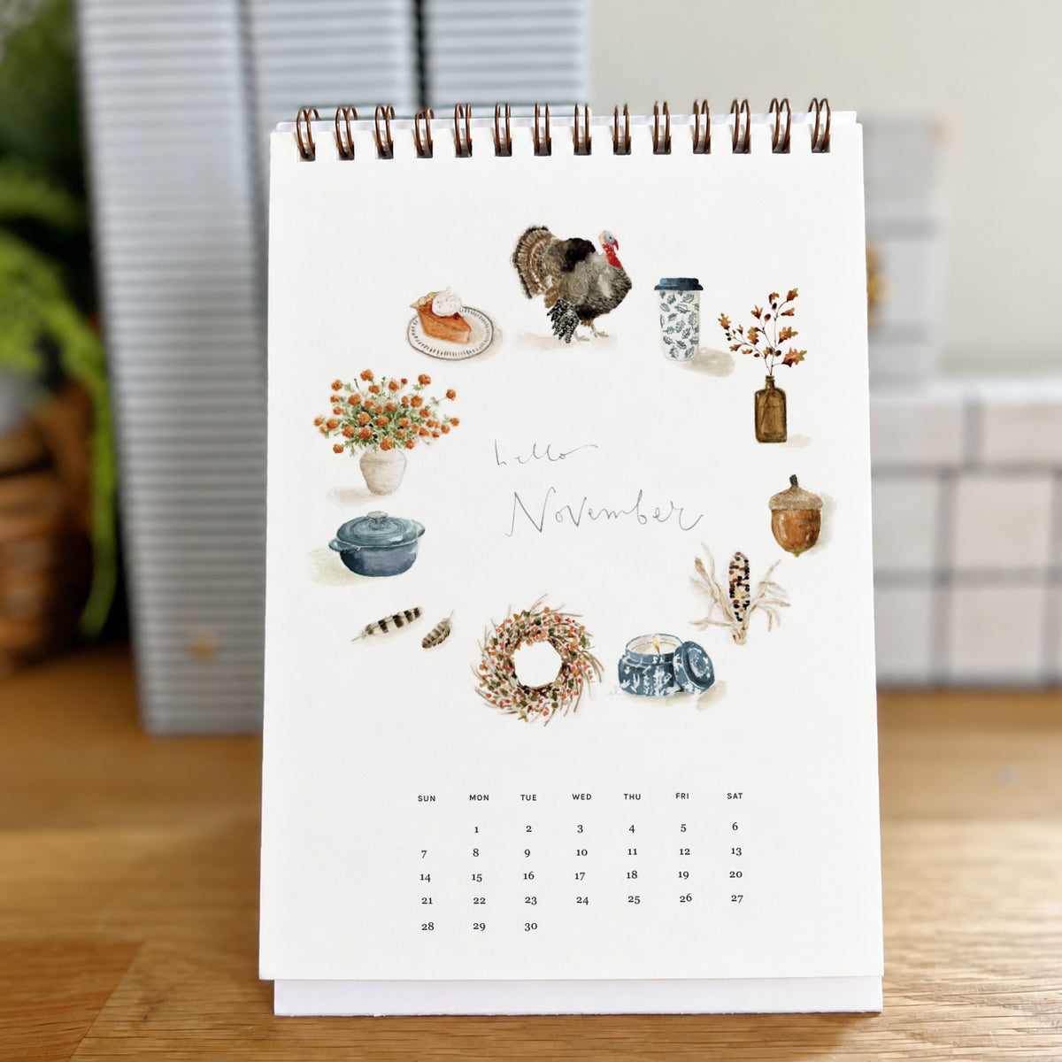 2027 hello month desk calendar November page with watercolor autumn icons like a turkey, pie, wreath, and acorn