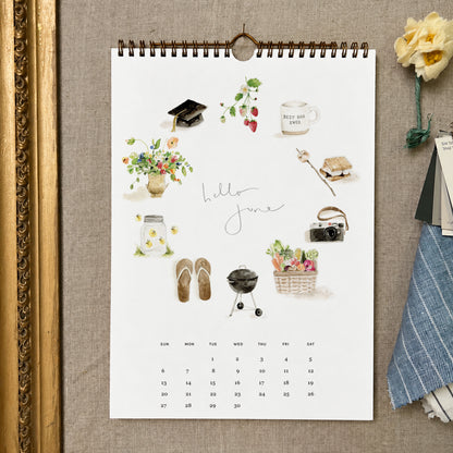 2027 hello month wall calendar June page with watercolor summer icons like strawberries, a camera, a grill, and flip-flops